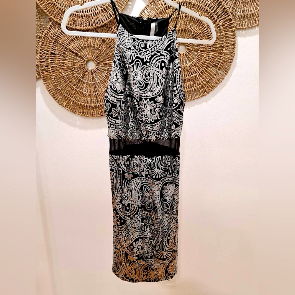 Black sequinned fitted mini dress with sheer panel at waist.